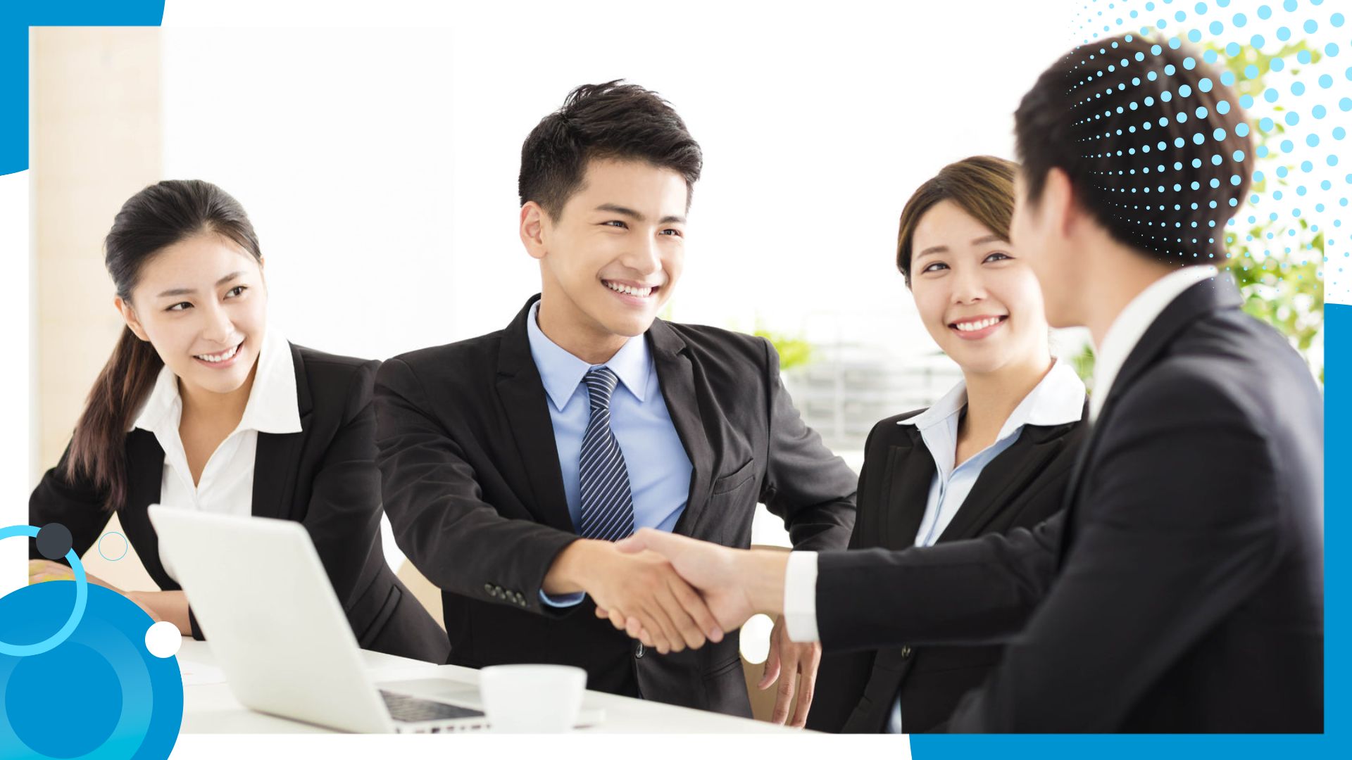 A group of professionals in a business meeting, smiling as two individuals shake hands, symbolizing collaboration and successful partnerships.